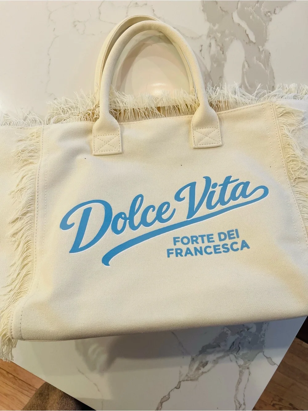 Dolce Vita Cream Canvas Fringe Tote with Light Blue Logo